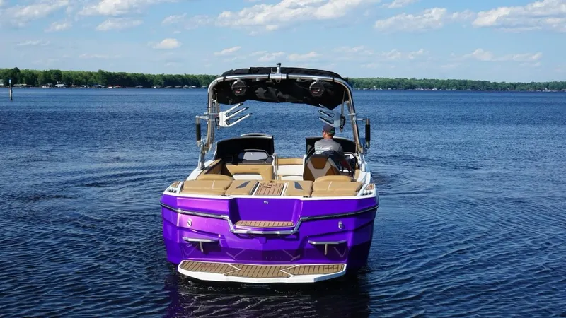 Slide: The Image of 2019 MasterCraft XStar boat on a lake with a vibrant purple exterior. - 5