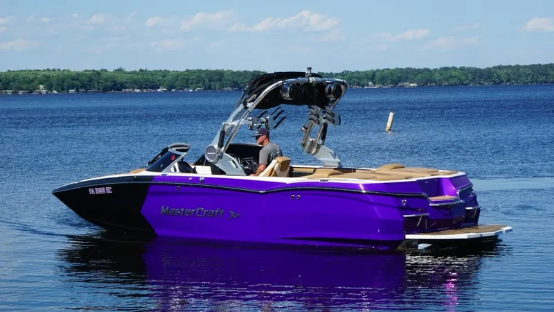 Slide: The Image of 2019 MasterCraft XStar boat in vibrant purple on a serene lake. - 6