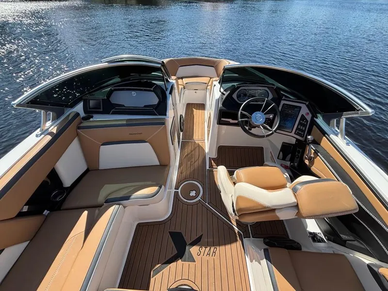 Slide: The Image of 2019 MasterCraft XStar boat interior with tan seating and sleek dashboard on water. - 9