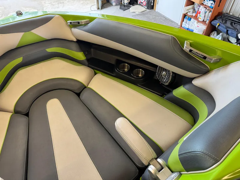 Slide: The Image of 2016 Malibu Wakesetter 23 LSV interior with green and gray seating, cup holders, and speaker. - 12