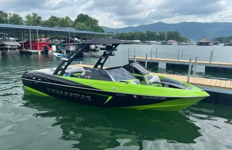Slide: The Image of 2016 Malibu Wakesetter 23 LSV boat in vibrant green, docked on a serene lake. - 4