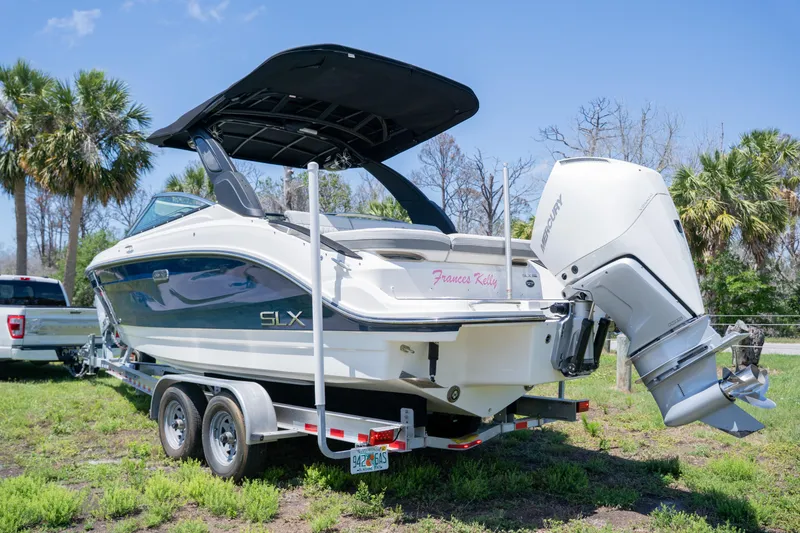 Slide: The Image of 2023 Sea Ray SLX 260 Outboard boat on trailer, parked outdoors with palm trees. - 3