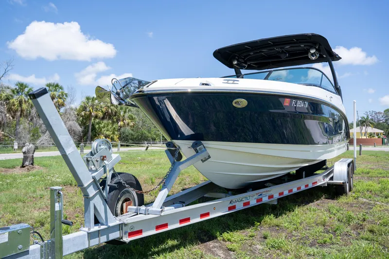 Slide: The Image of 2023 Sea Ray SLX 260 Outboard boat on trailer, parked on grass under blue sky. - 6