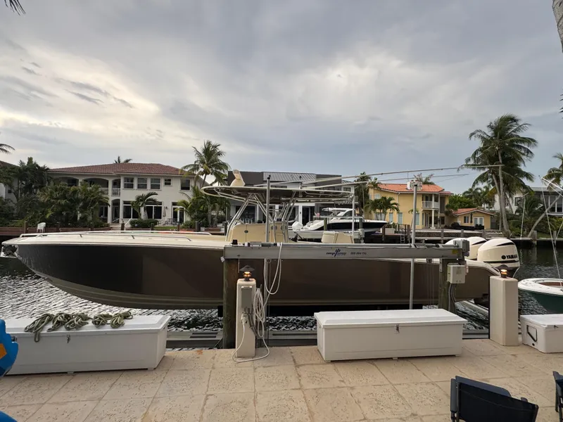 The Image of 2013 Bahama 41 boat docked by waterfront homes under cloudy sky. - 0