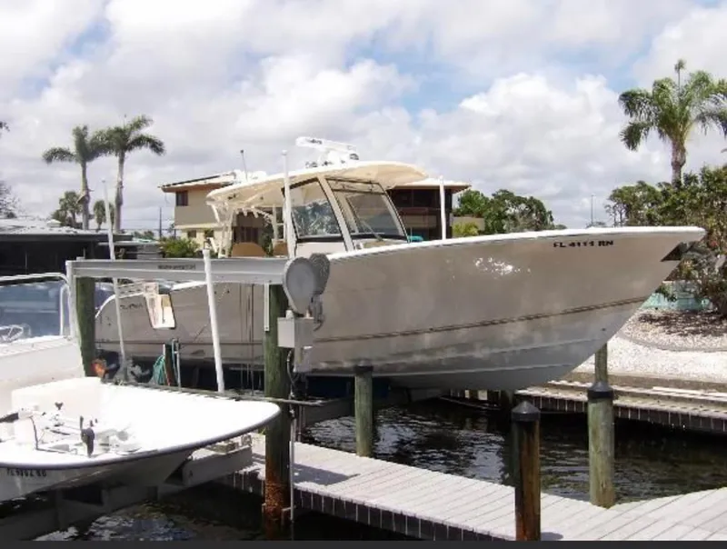 The Image of 2018 Cobia 344 Center Console boat docked near palm trees and waterfront homes. - 1