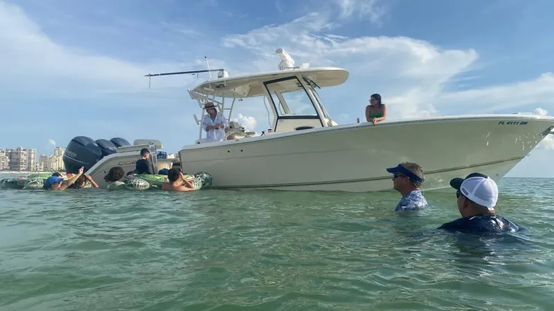 Slide: The Image of 2018 Cobia 344 Center Console boat with people enjoying water activities nearby. - 3
