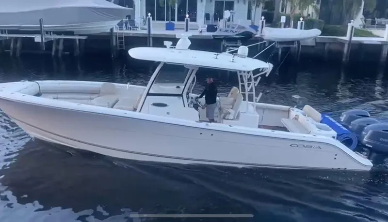 Slide: The Image of 2018 Cobia 344 Center Console boat docked in marina, featuring sleek design and triple engines. - 5