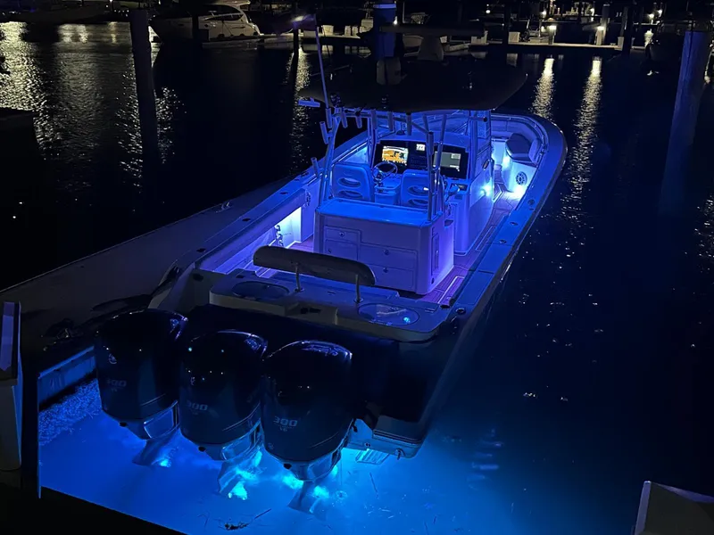 Slide: The Image of 2018 Cobia 344 Center Console boat illuminated with blue lights at night. - 6