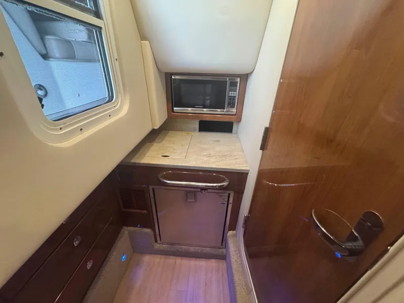 Slide: The Image of 2015 Formula 350 Crossover Bowrider interior with kitchenette, microwave, and wooden cabinetry. - 22