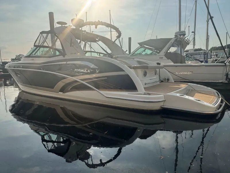 Slide: The Image of 2015 Formula 350 Crossover Bowrider boat docked in a marina, reflecting on calm water. - 5