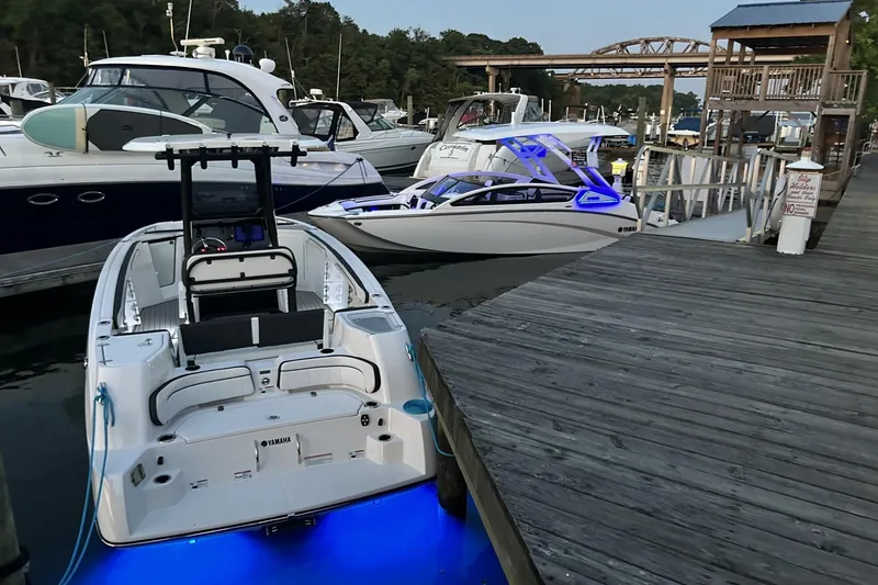 Slide: The Image of 2024 Yamaha Boats 275SD docked with blue LED lights, surrounded by other boats. - 10