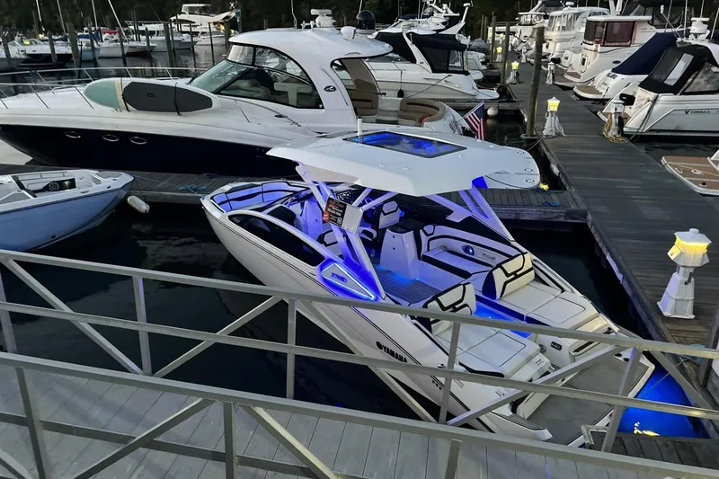Slide: The Image of 2024 Yamaha Boats 275SD docked, illuminated with blue lights, surrounded by other boats. - 9