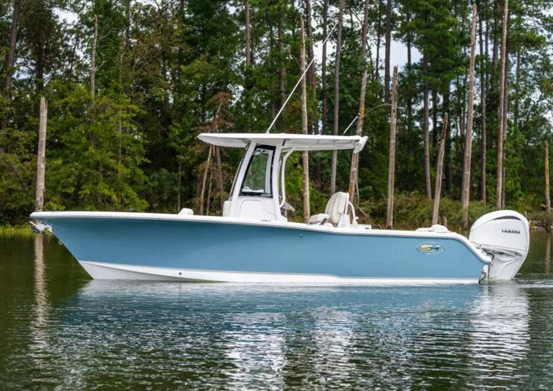 Slide: The Image of 2025 Sea Hunt Ultra 245 SE boat on calm water, surrounded by trees. - 21
