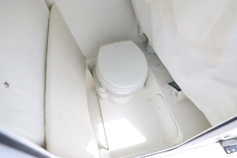 Slide: The Image of 2025 Sea Hunt Ultra 245 SE boat interior bathroom with toilet and white walls. - 5