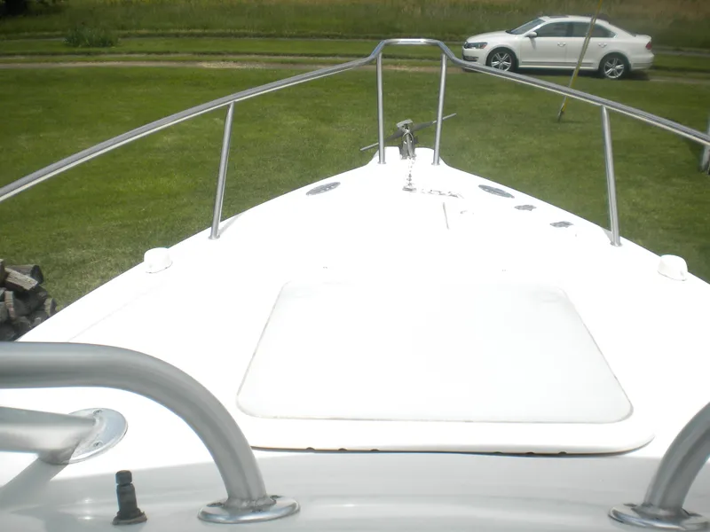 Slide: The Image of 2003 Pro-Line 23 Walk boat deck with railing, parked on grass near a white car. - 2