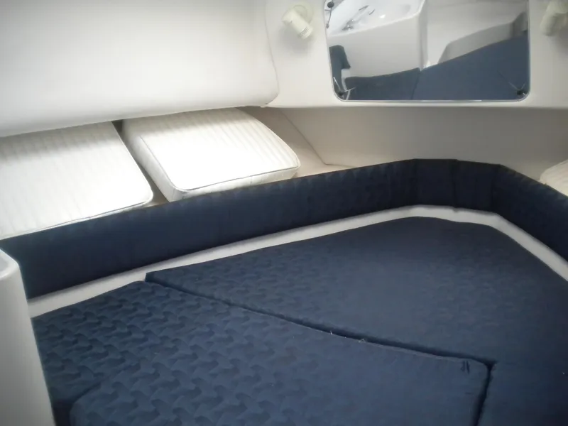 Slide: The Image of 2003 Pro-Line 23 Walk cabin interior with blue cushions and white pillows. - 20