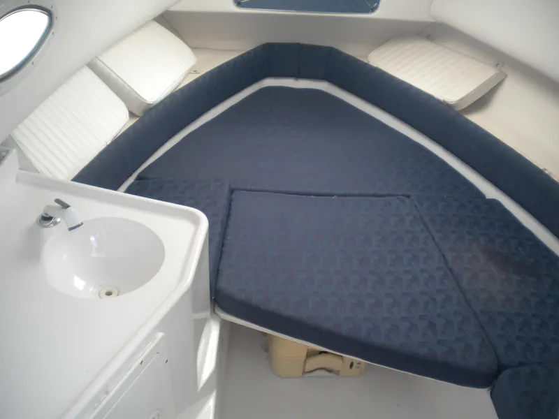Slide: The Image of 2003 Pro-Line 23 Walk cabin interior with blue cushions and compact sink. - 21