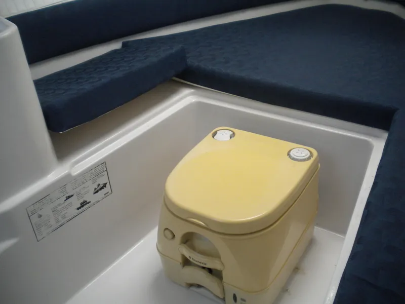Slide: The Image of 2003 Pro-Line 23 Walk boat interior with portable toilet and blue cushions. - 22