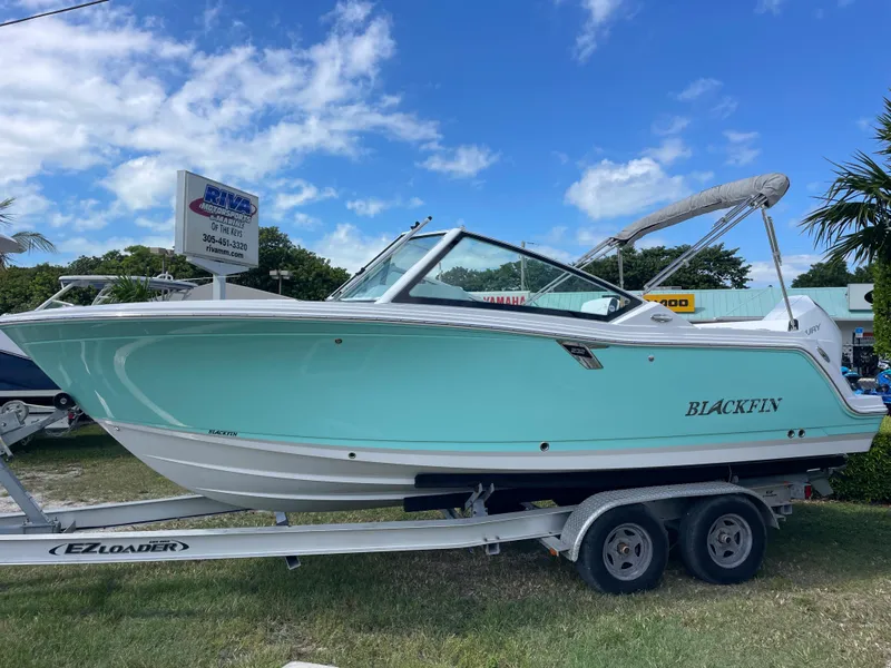 The Image of 2024 Blackfin 232DC boat on trailer, displayed outdoors under blue sky. - 1