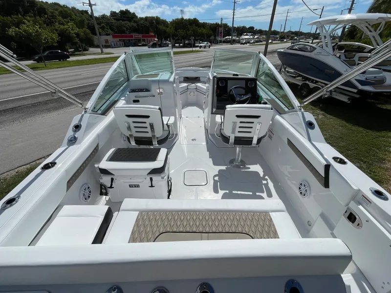 Slide: The Image of 2024 Blackfin 232DC boat interior with seating and console, parked near a road. - 4