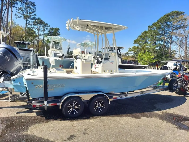 The Image of 2023 Pathfinder 2300 HPS boat on trailer, light blue hull, parked outdoors. - 0