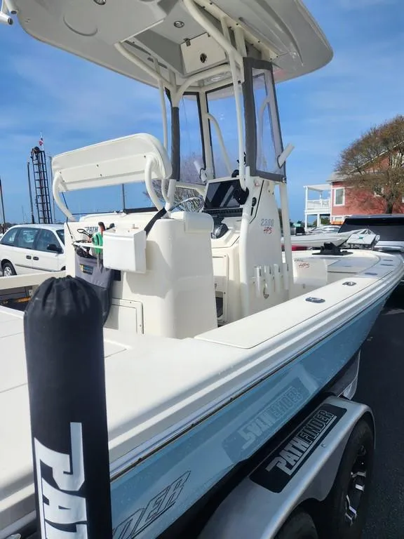 Slide: The Image of 2023 Pathfinder 2300 HPS boat with T-top and console, parked on a trailer. - 2