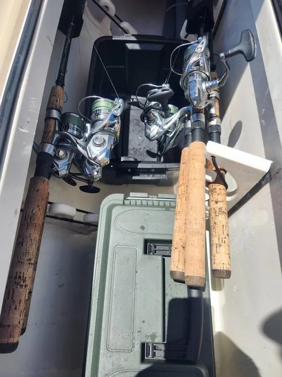 Slide: The Image of Fishing rods and gear in a 2023 Pathfinder 2300 HPS boat storage compartment. - 21