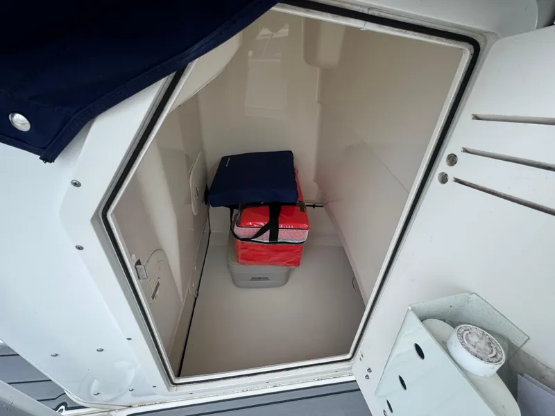 Slide: The Image of Storage compartment inside a 2013 Boston Whaler 210 Montauk boat, featuring a cooler and seat cushion. - 17