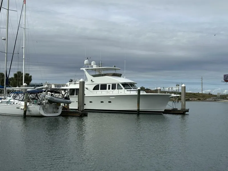 Slide: The Image of 2004 Cheoy Lee 72 yacht docked beside sailboats under cloudy skies. - 9