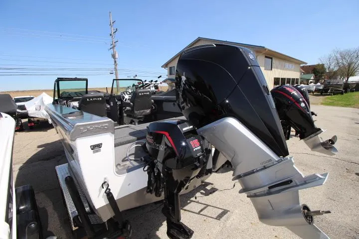 Slide: The Image of 2025 Lund 2075 Tyee boat with dual outboard motors, parked outdoors. - 2