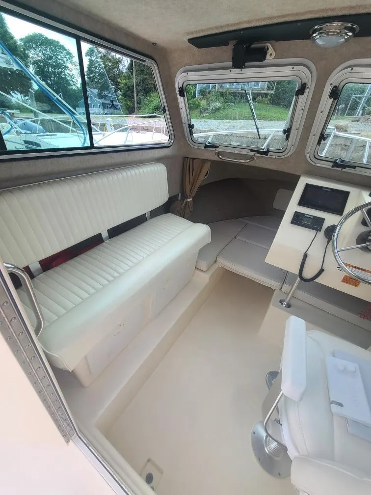 Slide: The Image of 2011 Parker 2120 Sport Cabin interior with white seating and steering console. - 12
