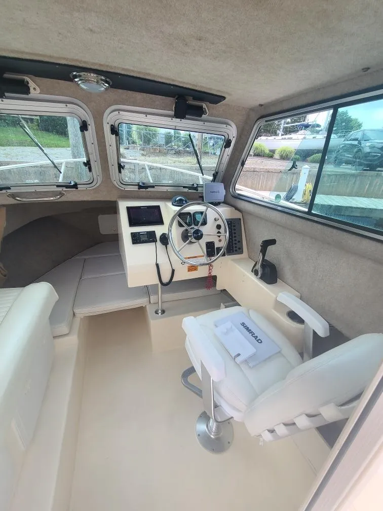 Slide: The Image of Interior of a 2011 Parker 2120 Sport Cabin boat, featuring steering wheel and seating. - 9