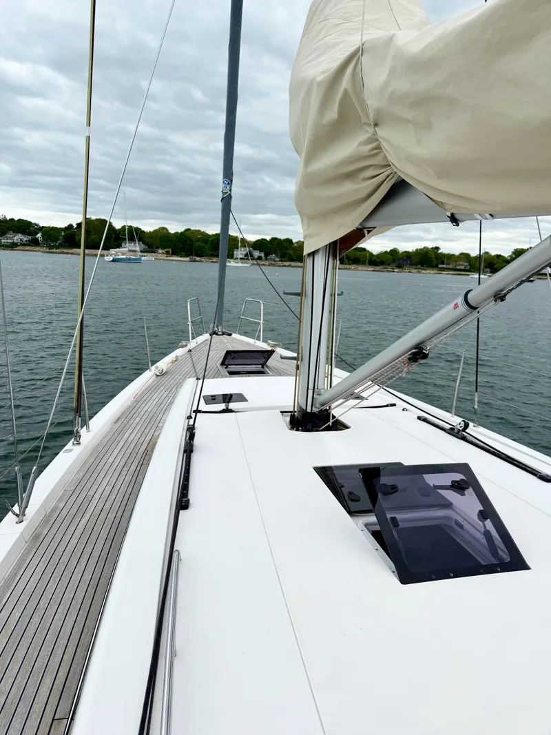 Slide: The Image of 2019 X-Yachts X4⁶ sailboat deck with mast and hatch, on calm water under cloudy sky. - 5