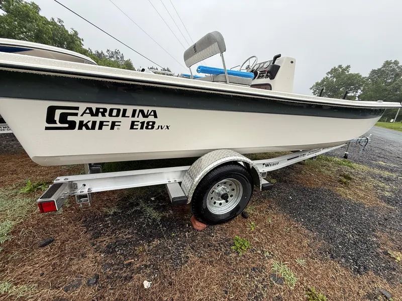 The Image of 2025 Carolina Skiff E18 JVX CC boat on trailer, parked outdoors. - 0