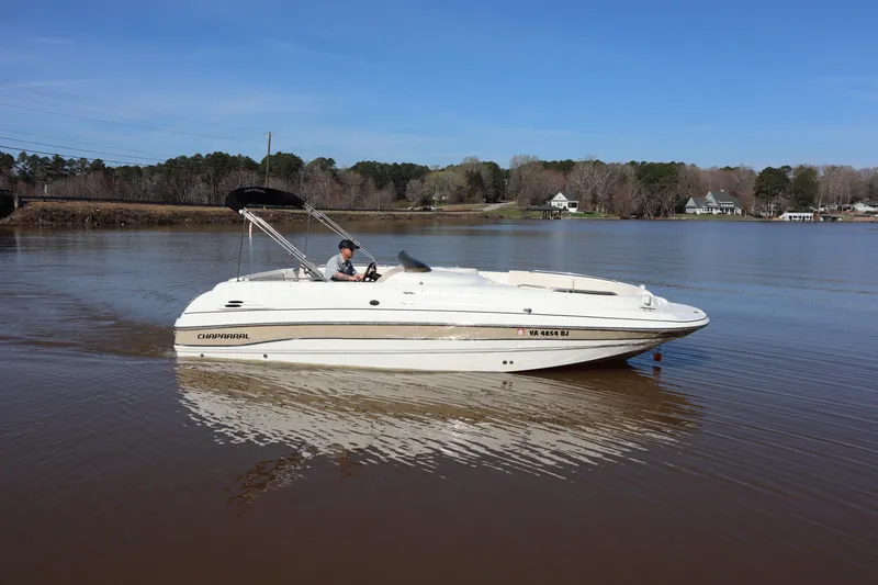 The Image of 2000 Chaparral Sunesta 232 boat cruising on a calm lake under a clear blue sky. - 1