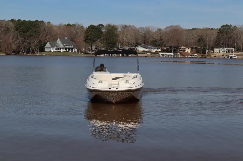 Slide: The Image of Chaparral Sunesta 232 boat on a calm lake, 2000 model, with houses in the background. - 4