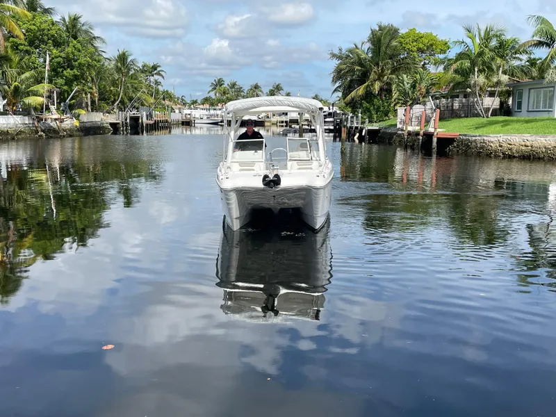 Slide: The Image of 2022 World Cat 255 DC boat cruising on a calm, tropical waterway with palm trees. - 10