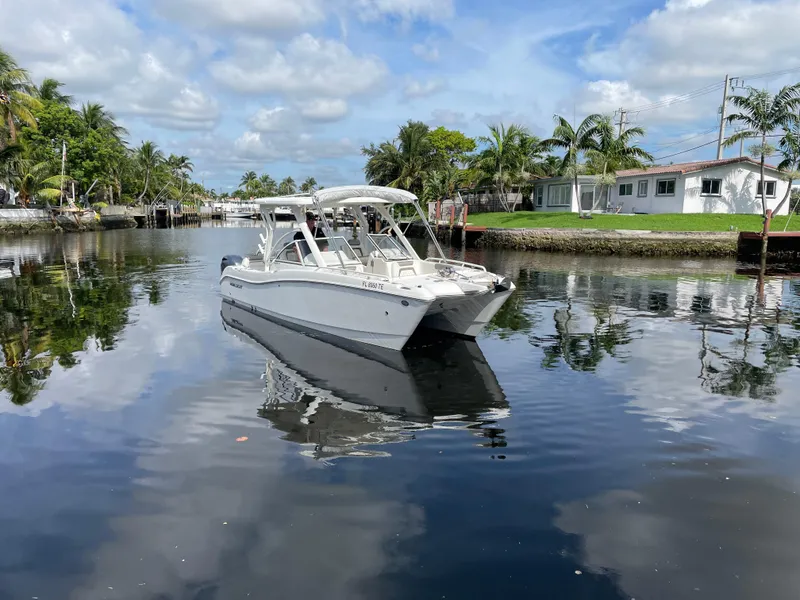 Slide: The Image of 2022 World Cat 255 DC boat on a calm canal with palm trees and houses. - 11