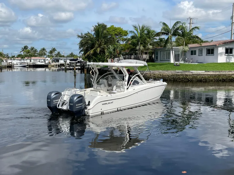 Slide: The Image of 2022 World Cat 255 DC boat on a calm waterway with palm trees and houses. - 14