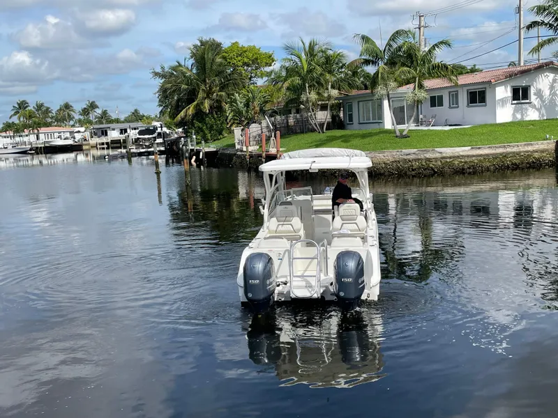 Slide: The Image of 2022 World Cat 255 DC boat cruising on a calm canal near waterfront homes and palm trees. - 15