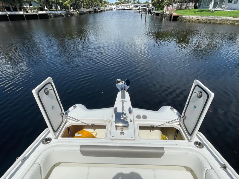 Slide: The Image of 2022 World Cat 255 DC boat on calm waterway, open storage compartments visible. - 16