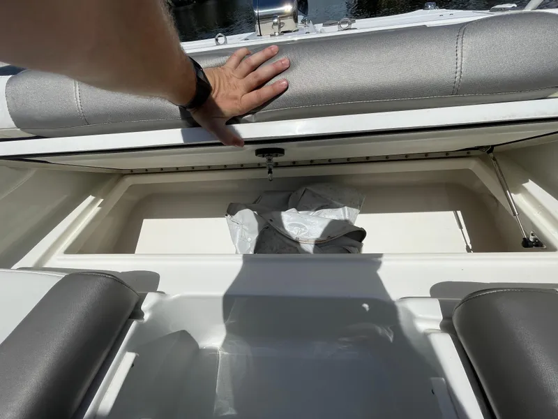 Slide: The Image of 2022 World Cat 255 DC boat storage compartment with gray seating and hand opening lid. - 17