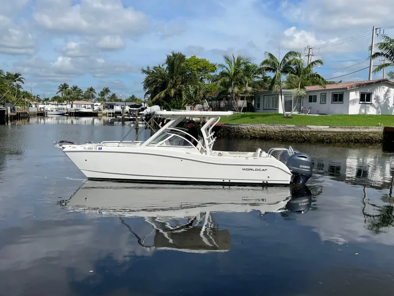 Slide: The Image of 2022 World Cat 255 DC boat on a calm waterway, surrounded by palm trees and houses. - 5