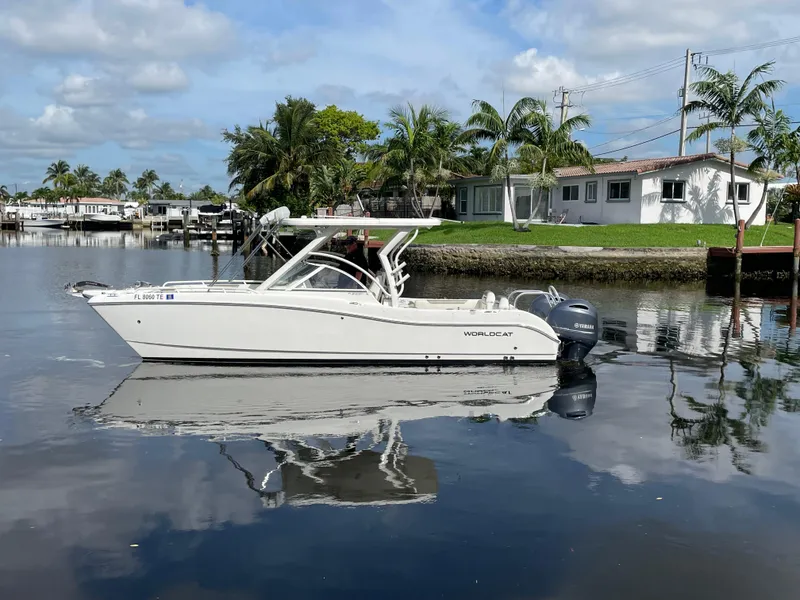 Slide: The Image of 2022 World Cat 255 DC boat on calm water near a residential area with palm trees. - 6