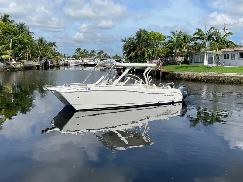 Slide: The Image of 2022 World Cat 255 DC boat on a calm canal with palm trees and houses. - 8