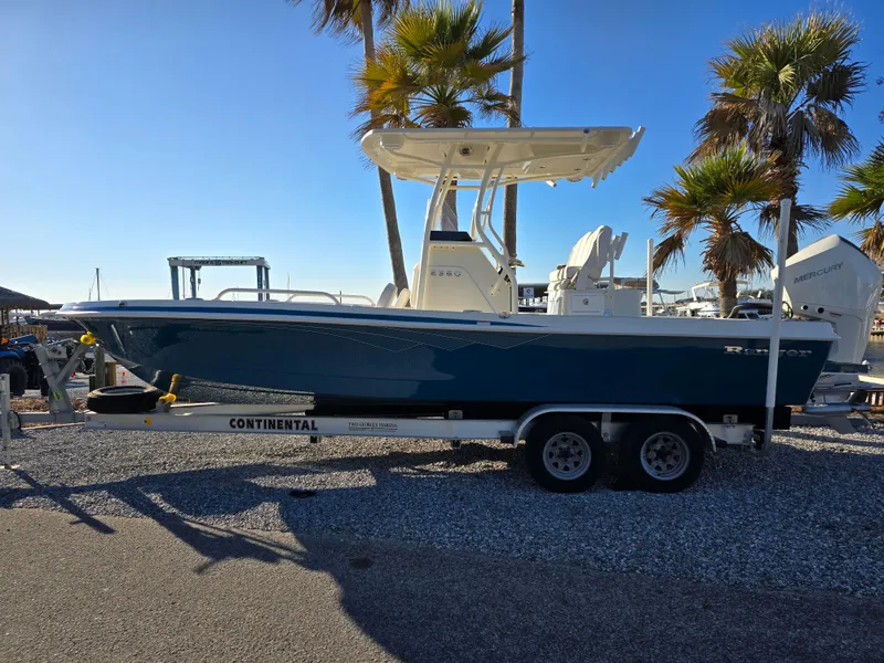 Slide: The Image of 2025 Ranger 2360 Bay boat on trailer, parked near palm trees under clear blue sky. - 0