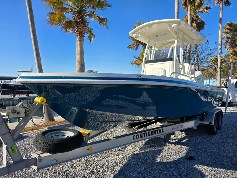 Slide: The Image of 2025 Ranger 2360 Bay boat on trailer, parked under palm trees. - 3