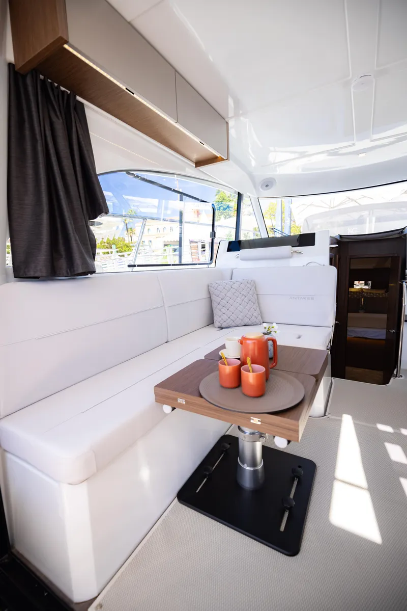 Slide: The Image of 2026 Beneteau Antares 11 interior with white seating and wooden table. - 12