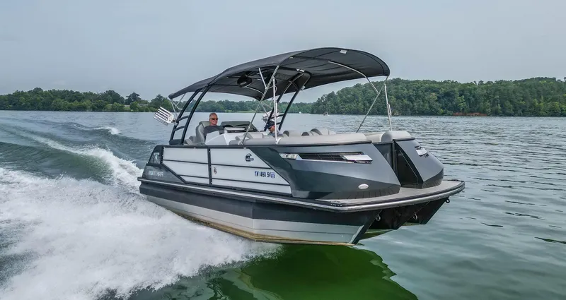 Slide: The Image of 2022 Montara MT 2.0 25 CW boat cruising on a lake with lush green surroundings. - 1