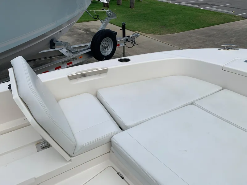 Slide: The Image of 2024 Pathfinder 2400 TRS boat interior with white cushioned seating and trailer in background. - 27